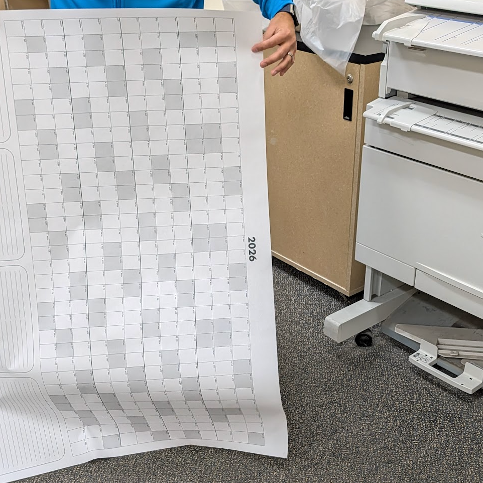 Person holding a large sheet of gray and white checkered paper in an office setting.
